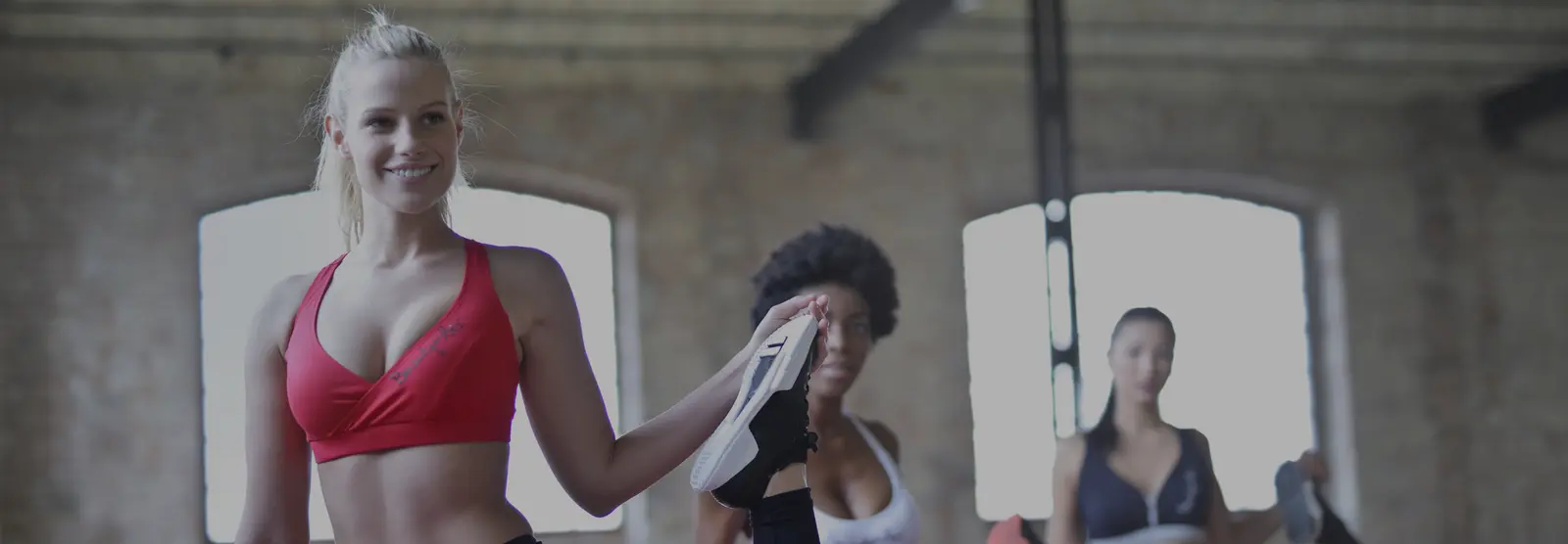 Three women in the gym, stretching before a group workout